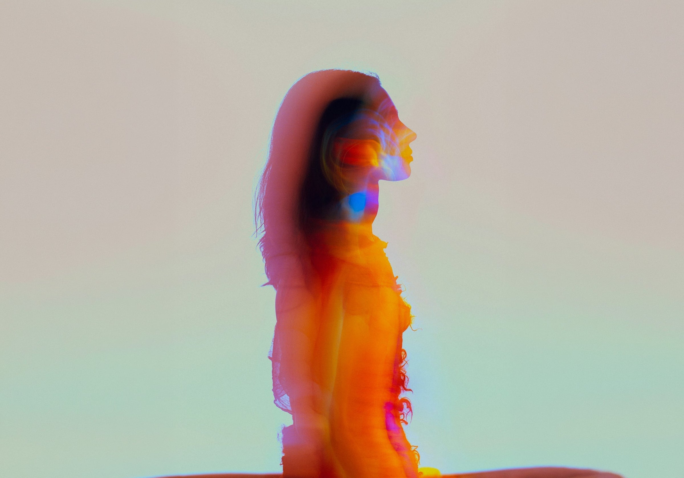 Colourful blurred silhouette of a seated woman, cover image for how Specialised Kinesiology works