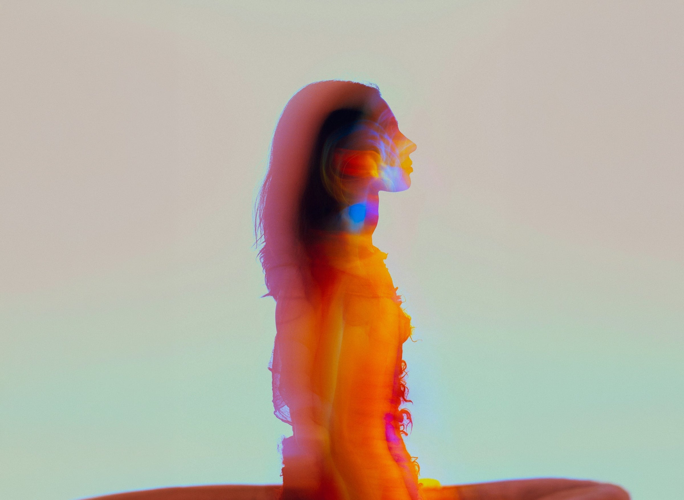 Colourful blurred silhouette of a seated woman, cover image for how Specialised Kinesiology works