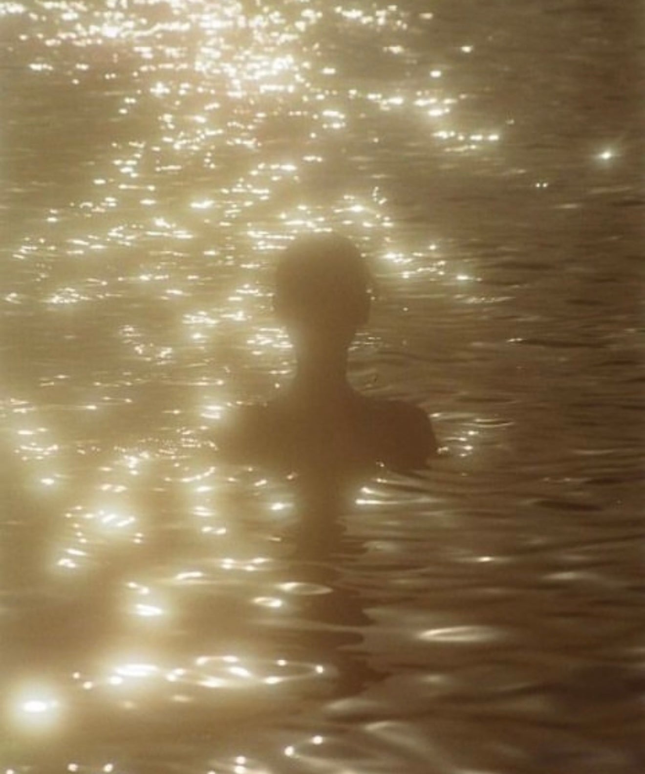 Gold sunset and shimmering water with lady bathing