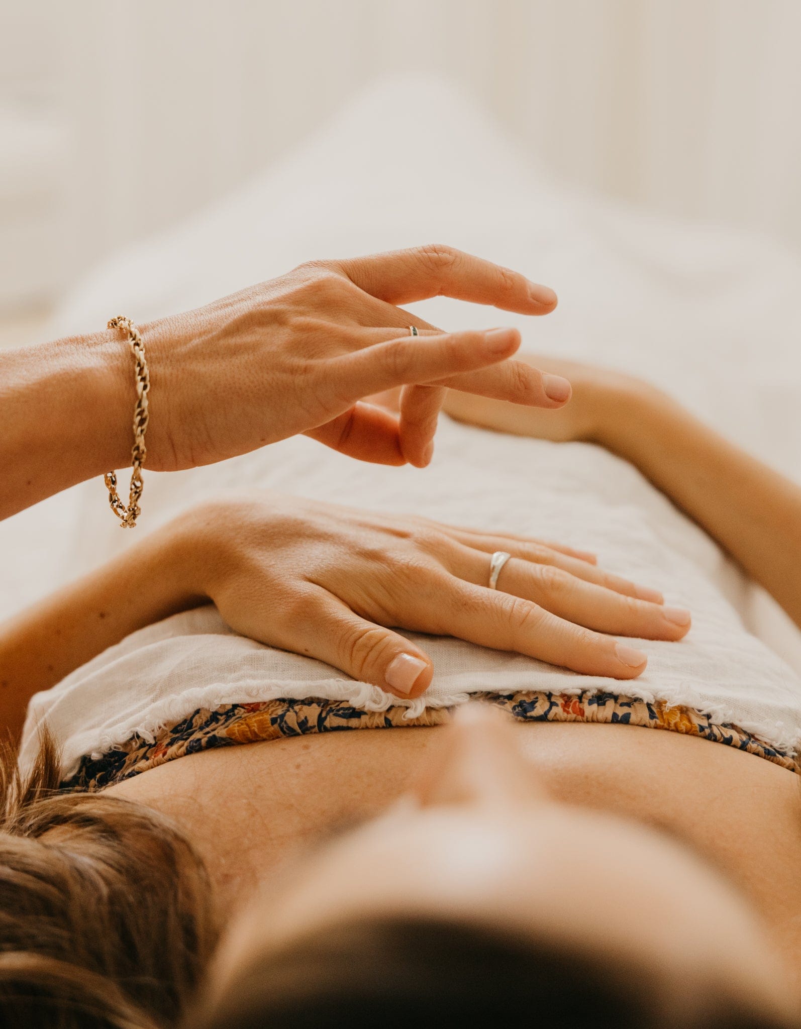 Practitioner's hands held above a client during a Specialised Kinesiology session, cover image for recovering from burnout