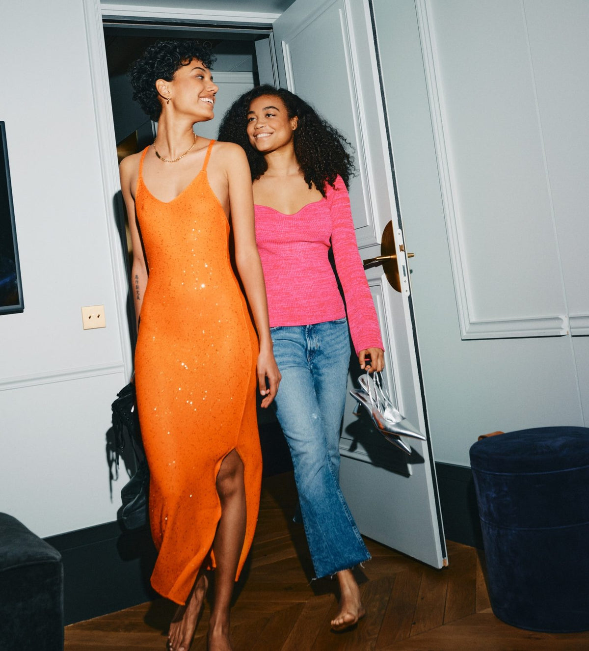 Two women walking into a room, smiling